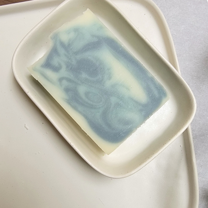 Dark Charm Natural Handmade Soap is a calming, nourishing soap crafted with skin-loving ingredients and a grounding, earthy, musky, smoky fragrance that envelops your senses. The deep, woody aroma of dark patchouli, vetiver, and cedarwood essential oils creates a tranquil, nature-inspired experience, bringing a sense of serenity to your bath. This luxurious bar offers a gentle, soothing cleanse without stripping or drying your skin.